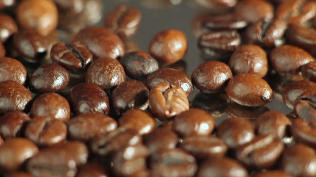 Roasted coffee beans rotates on the table. close-up