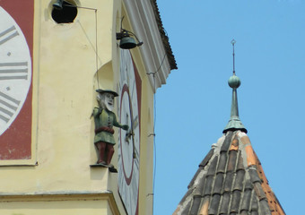 Fototapeta na wymiar Small statue of man high on top of the Saxon Tower in Medias, Romania.