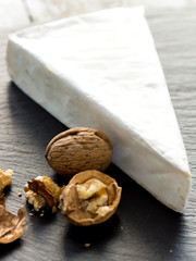 Brie cheese with walnut on a stone background