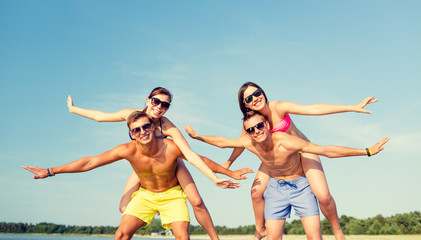 Obraz premium smiling friends having fun on summer beach