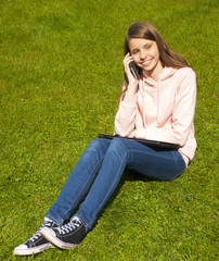 Beautiful girl with phone on the grass 