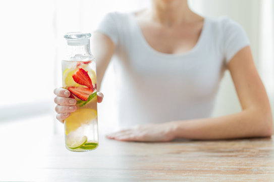 Close Up Of Woman With Fruit Water In Glass Bottle