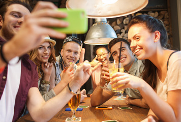 happy friends with smartphone taking selfie at bar