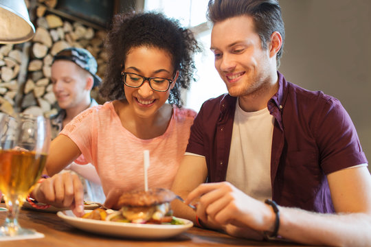 Happy Friends Eating And Drinking At Bar Or Pub