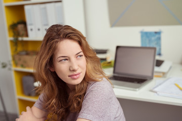 studentin sitzt am schreibtisch und schaut nachdenklich aus dem fenster