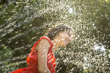 Laughing woman cooling off under a spray of water