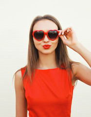 Portrait of pretty woman in the red sunglasses blowing lips havi