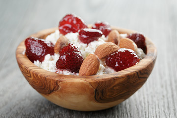 cottage cheese with preserved strawberry in wood bowl on oak