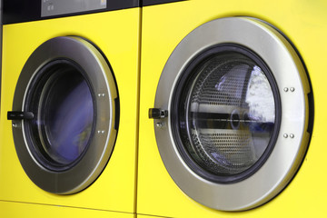 two yellow  washing machines in laundromats
