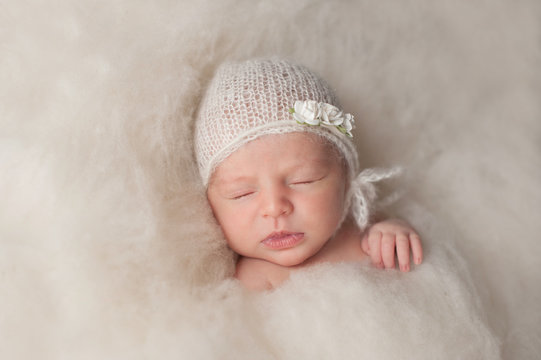 Newborn Baby Girl Wearing a White Knitted Bonnet