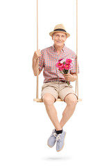 Senior gentleman sitting on swing and holding flowers