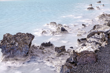 Rocks and warm waters rich in minerals like silica and sulfur in the Blue Lagoon near Reykjavik, Iceland.
