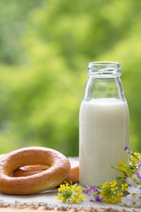 Bottle of milk and bagels in summer time