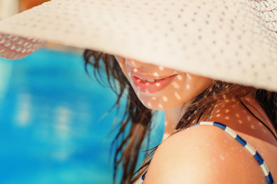 beautiful girl in a hat relaxing near a swimming pool
