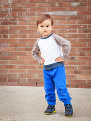 Toddler boy by brick wall laughing