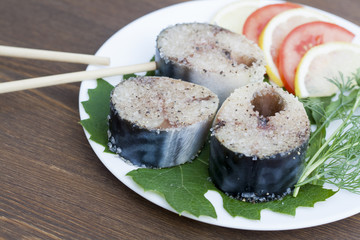Pieces of fresh mackerel in spices with vegetables on white plate