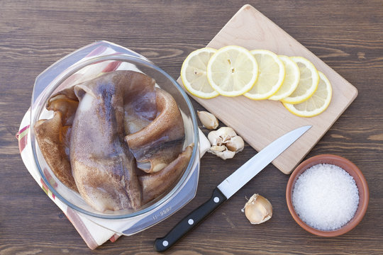 Fresh squid carcass in a glass pot with herbs and sliced lemon