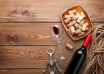 Red wine bottle, wine glass, bowl with corks and corkscrew