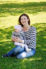 Portrait of mother and daughter, happy family of two, on the meadow in the park outside on a spring summer bright day, hugging, kissing and playing. Mothers Day