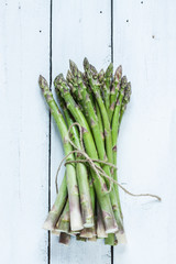 Bunch of asparagus on white planked wood table from above