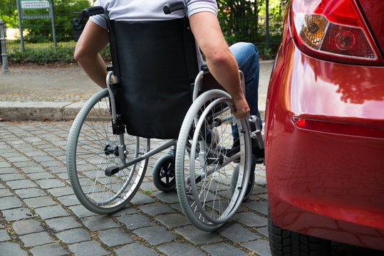 Disabled Man Sitting On A Wheelchair Near His Car