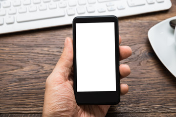 Person Hands Holding Mobile Phone At Desk