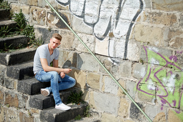 Fototapeta premium Young man with smartphone, sitting on a stairway