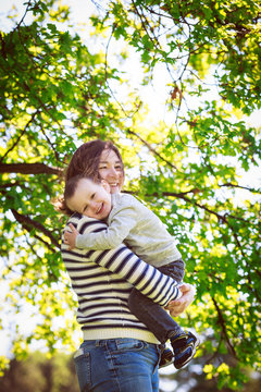 Portrait of mother and son, happy family of two, on the meadow in the park outside on a spring summer bright day, hugging, kissing and playing. Mothers Day