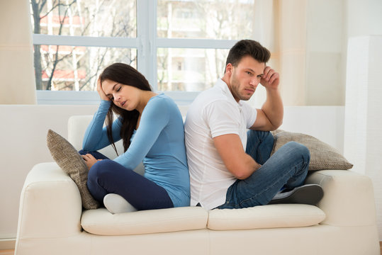 Displeased Couple Sitting On Couch After Quarrel