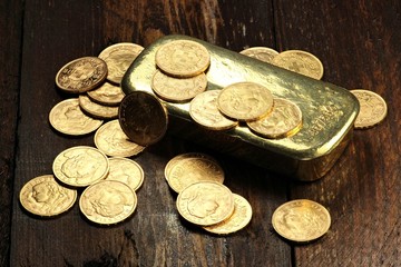 schweizer Goldvreneli mit Goldbarren auf rustikalem Holzhintergrund