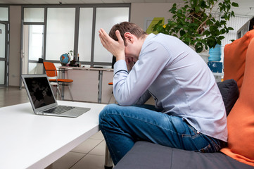 Young handsome man with computer in the office.