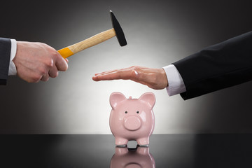 Businessman Saving Piggybank From Hammering
