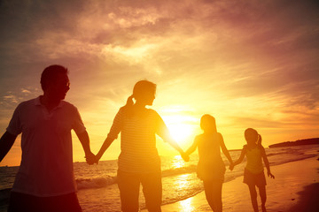 The silhouette of happy family walking on the beach