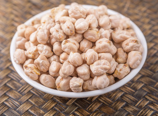 Chickpeas in a white bowl on wooden board