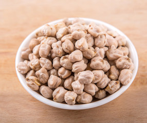 Chickpeas in a white bowl on wooden board