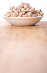 Chickpeas in a white bowl on wooden board