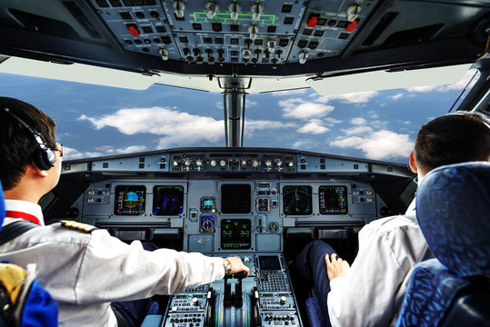 Pilots in the plane cockpit and cloudy sky