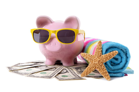 Piggy Bank or piggybank wearing sunglasses standing on pile heap of US American dollar bills with beach towel holiday vacation retirement saving money plan photo isolated white background