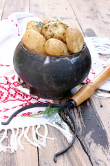Cast iron pot with potatoes on wooden table