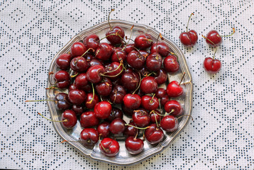 Sweet cherry in metal plate on white tablecloth