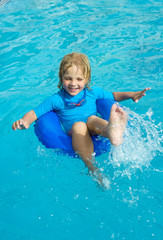 Fototapeta na wymiar Smiling little girl in swimming goggles relaxing in the swimming pool