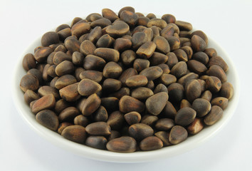 Handful of pine nuts on a white porcelain dish