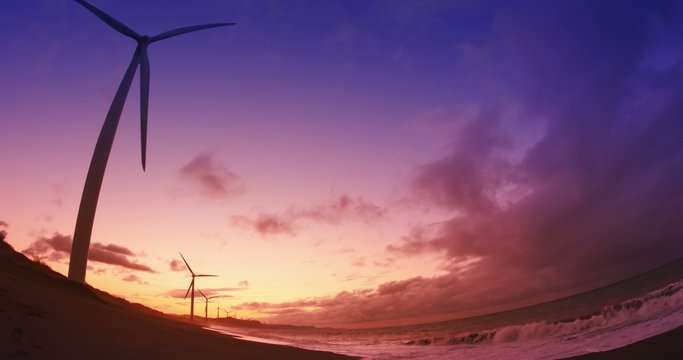 Beautiful subset in sea shore with many wind mill turbines spinning