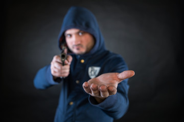 A person in a hoodie is aiming and holding the other hand. A concept of the robbery.