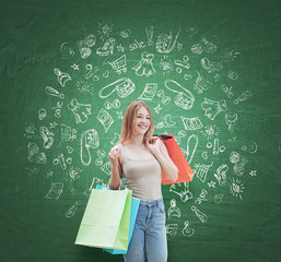 A happy young woman with the colourful shopping bags from the fancy shops. Shopping icons are drawn on the green wall.