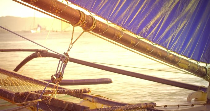 Knots and ropes of small sail boat with sun light reflecting on water