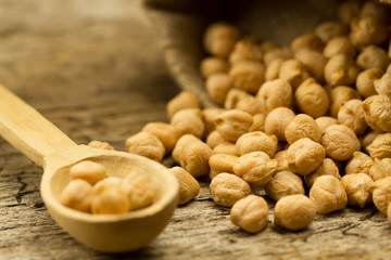 scattered chickpeas from a jute bag with a spoon on old wooden background