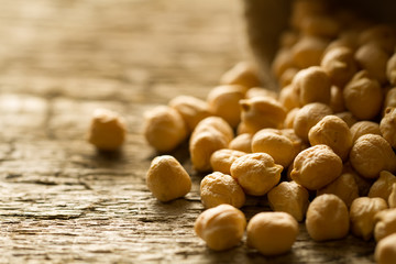 scattered chickpeas from a jute bag on old wooden background