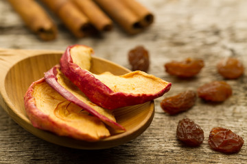 dried apples with cinnamon sticks and raisins on the old wooden background. Closeup.