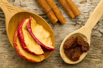 dried apples with cinnamon sticks and raisins on the old wooden background. Closeup.